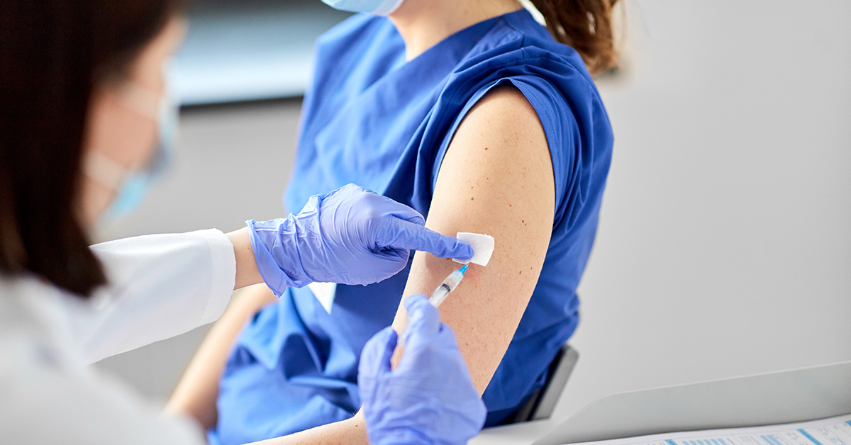 En kvinna får en vaccinationsdos i överarmen.