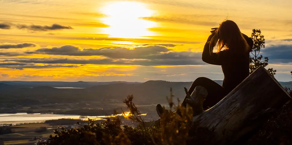 Person sitter på berg och kollar på solnedgången